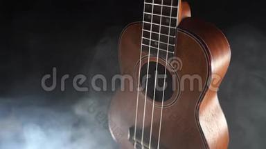 红木夏威夷四弦琴吉他在黑色背景下与烟雾隔离